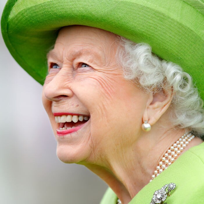 A close up of Queen Elizabeth wearing lime green hat and dress smiling brightly