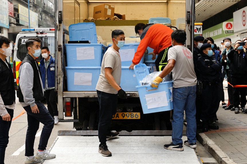 Movers collect boxes of evidence into a van after a police search at the office of Stand News.