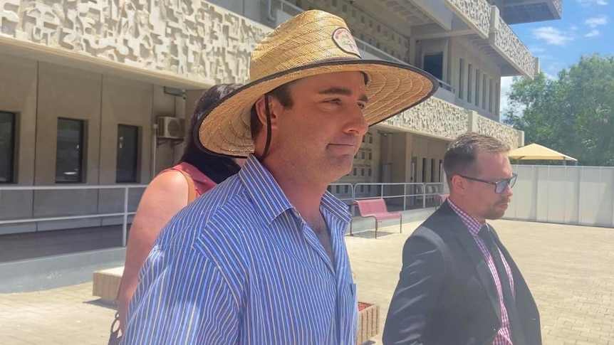 A man in a blue shirt with stripes and a straw hat leaving Townsville Court