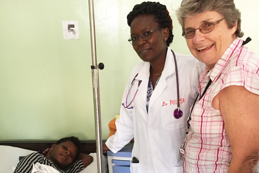 Gwen Wetzig stands alongside a patient in bed with medical colleague Dr Polisi at a teaching hospital in Goma in Congo.
