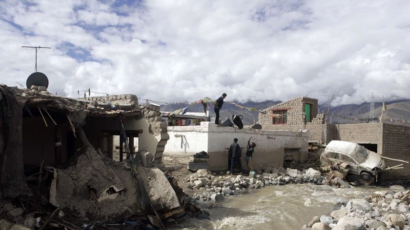 Flash flood victims retrieve their belongings from their partially damaged house in Leh