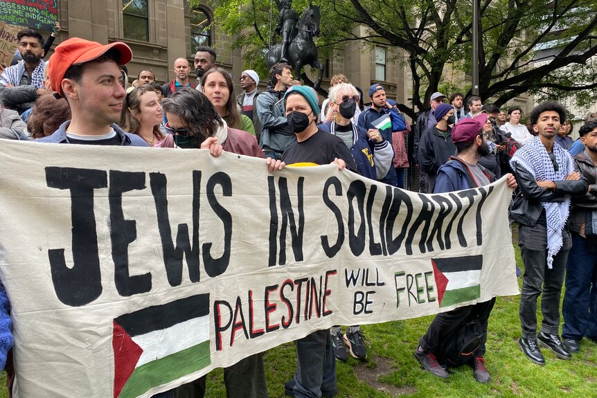 People hold up a 'Jews in solidarity' banner at a rally.