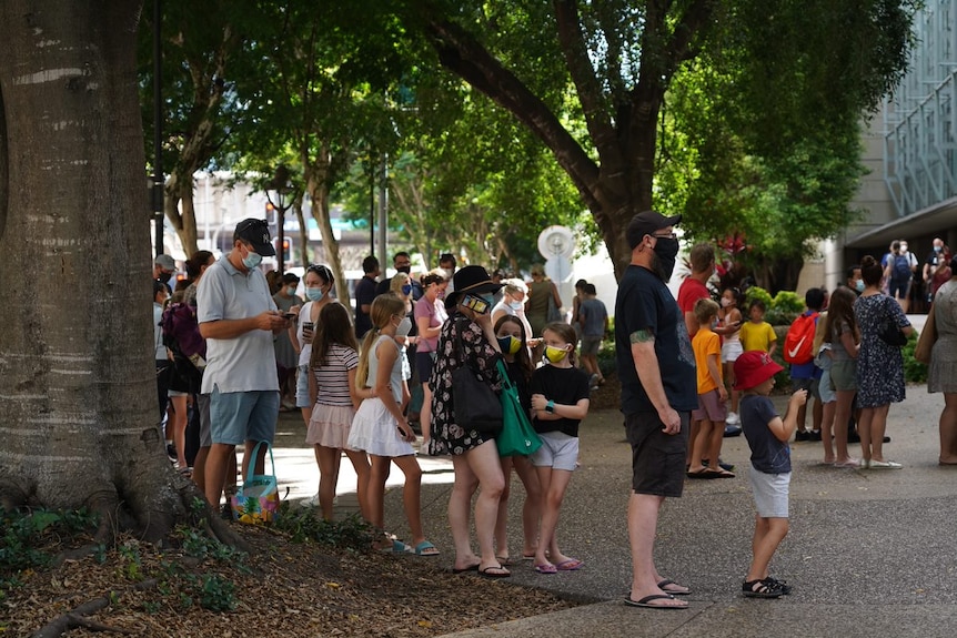 People stand in line, including children.