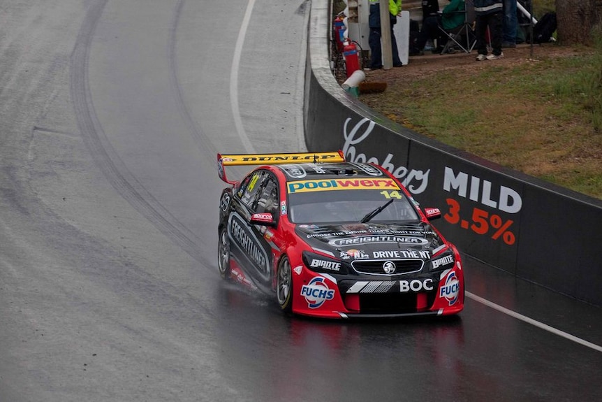 A car drives around Mt Panorama in the wet.