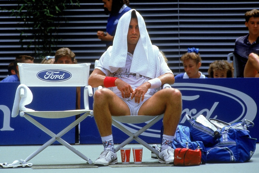 Pat Cash sits under a towel on his head