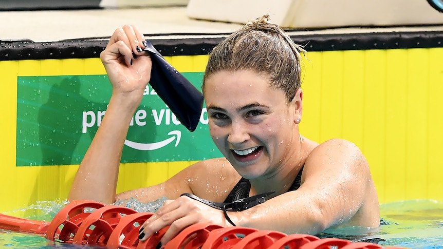 Young woman smiles while in water at end of swimming pool