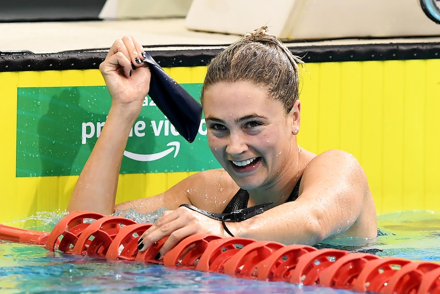 Young woman smiles while in water at end of swimming pool