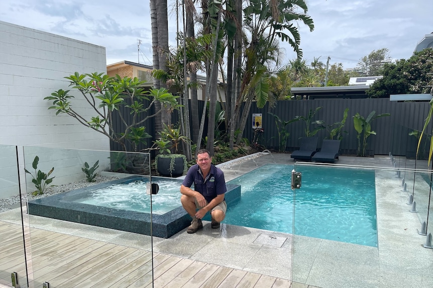 middle aged man crouching next to pool 