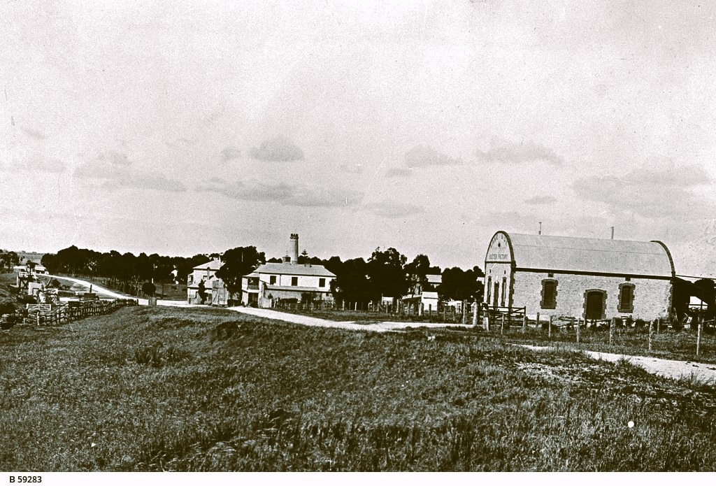 A black and white photograph showing a building with a barrel roof next to a road that also runs past 