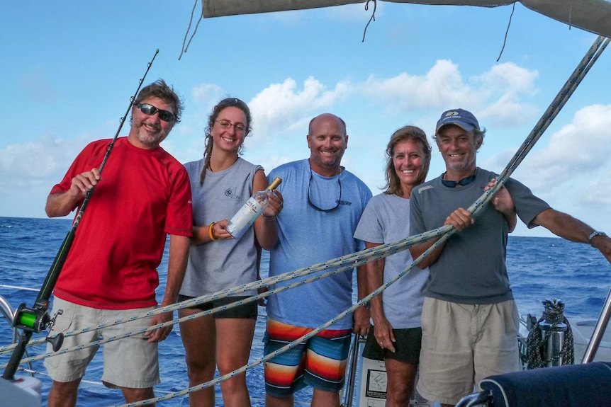 The crew members of sailing catamaran 'Vivo' stand on board holding the message filled bottle moments before it was released.