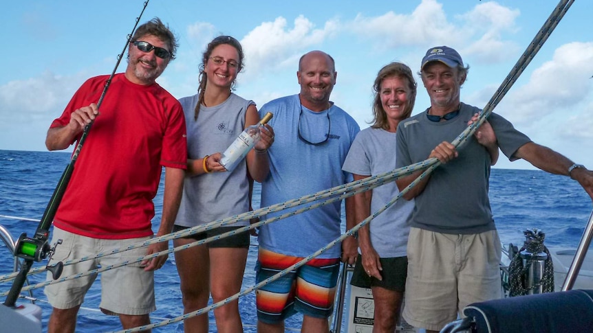 The crew members of sailing catamaran 'Vivo' stand on board holding the message filled bottle moments before it was released.
