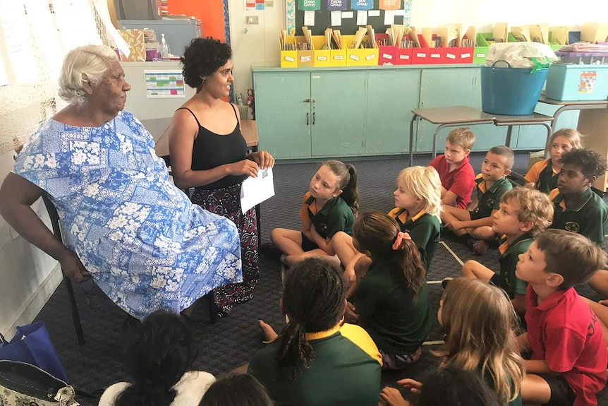 Students sit on floor of classroom at Mossman State School in far north Queensland, with teacher and Indigenous elder.