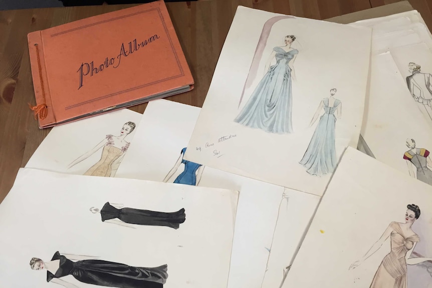 fashion illustrations and a photo album spread across a table