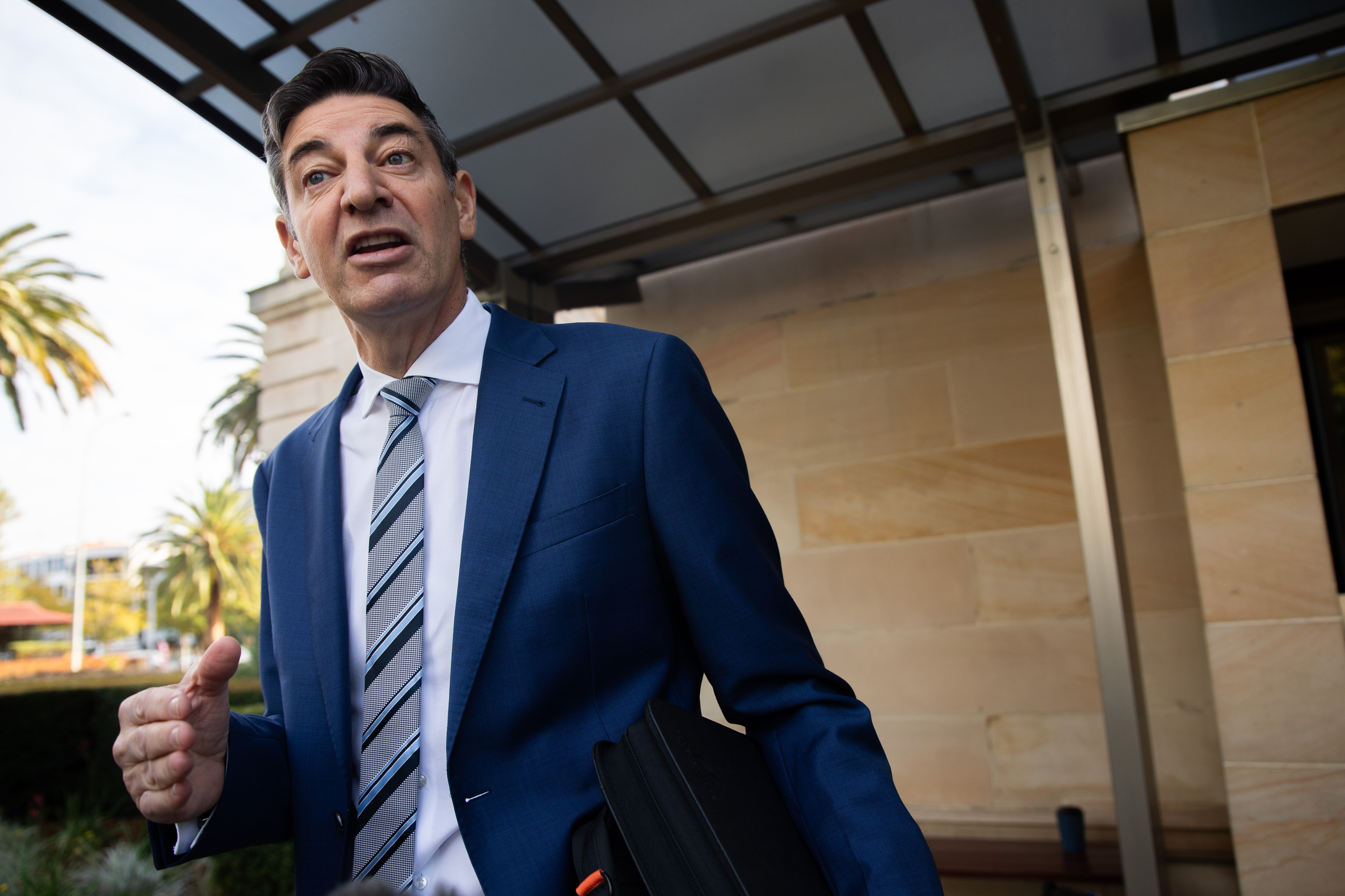 Basil Zempilas stands in a suit, speaking.