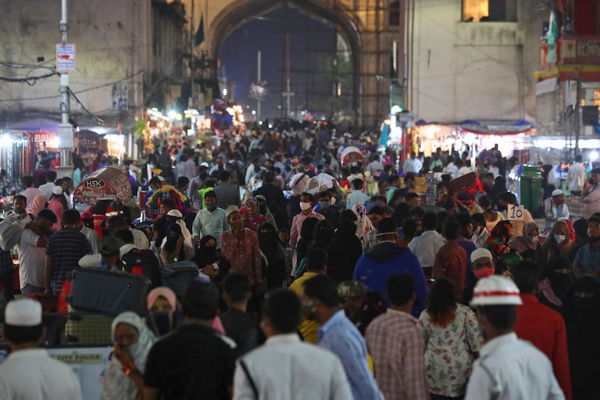 People wear face masks at a crowded street market in India