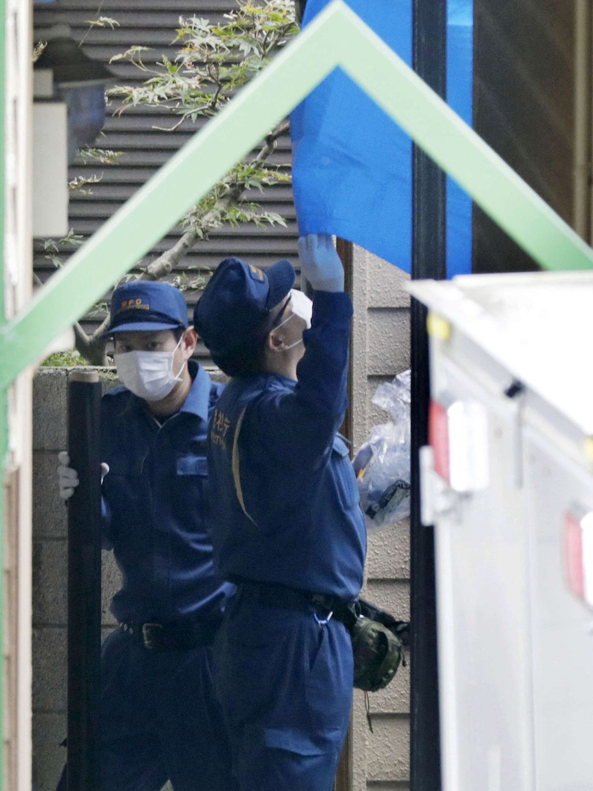Two policemen wearing face masks examine a property.