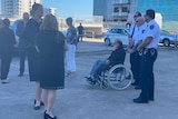 A man in a wheelchair with sheriffs officers and other people