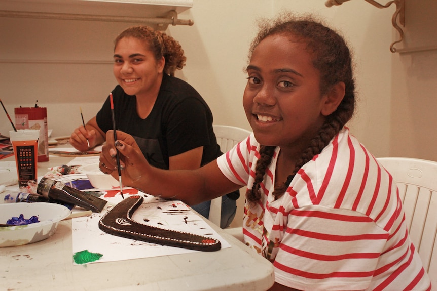 two young girls painting boomerangs