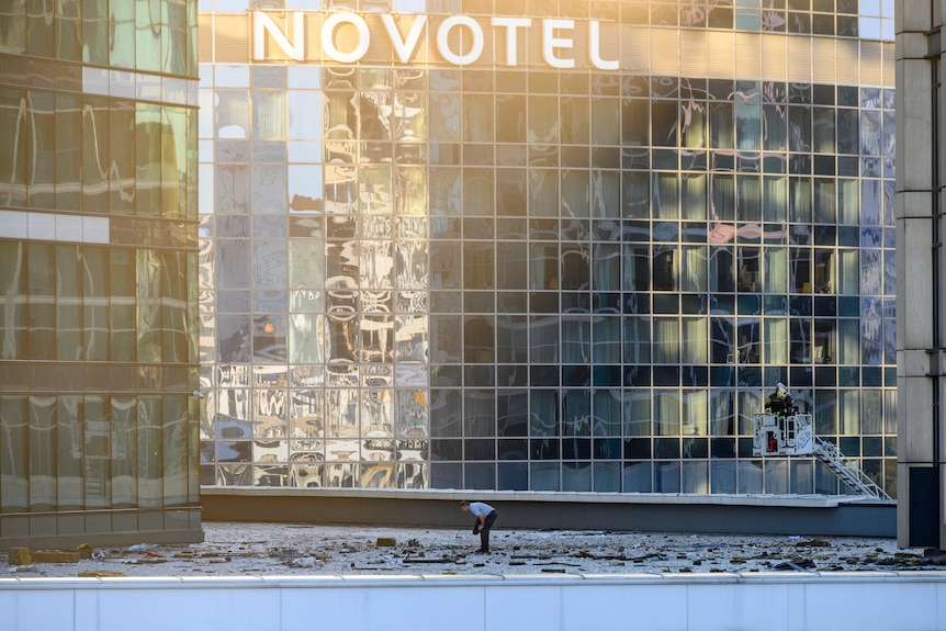 A man examines an area next t o a Novotel building damaged by a drone attack. 
