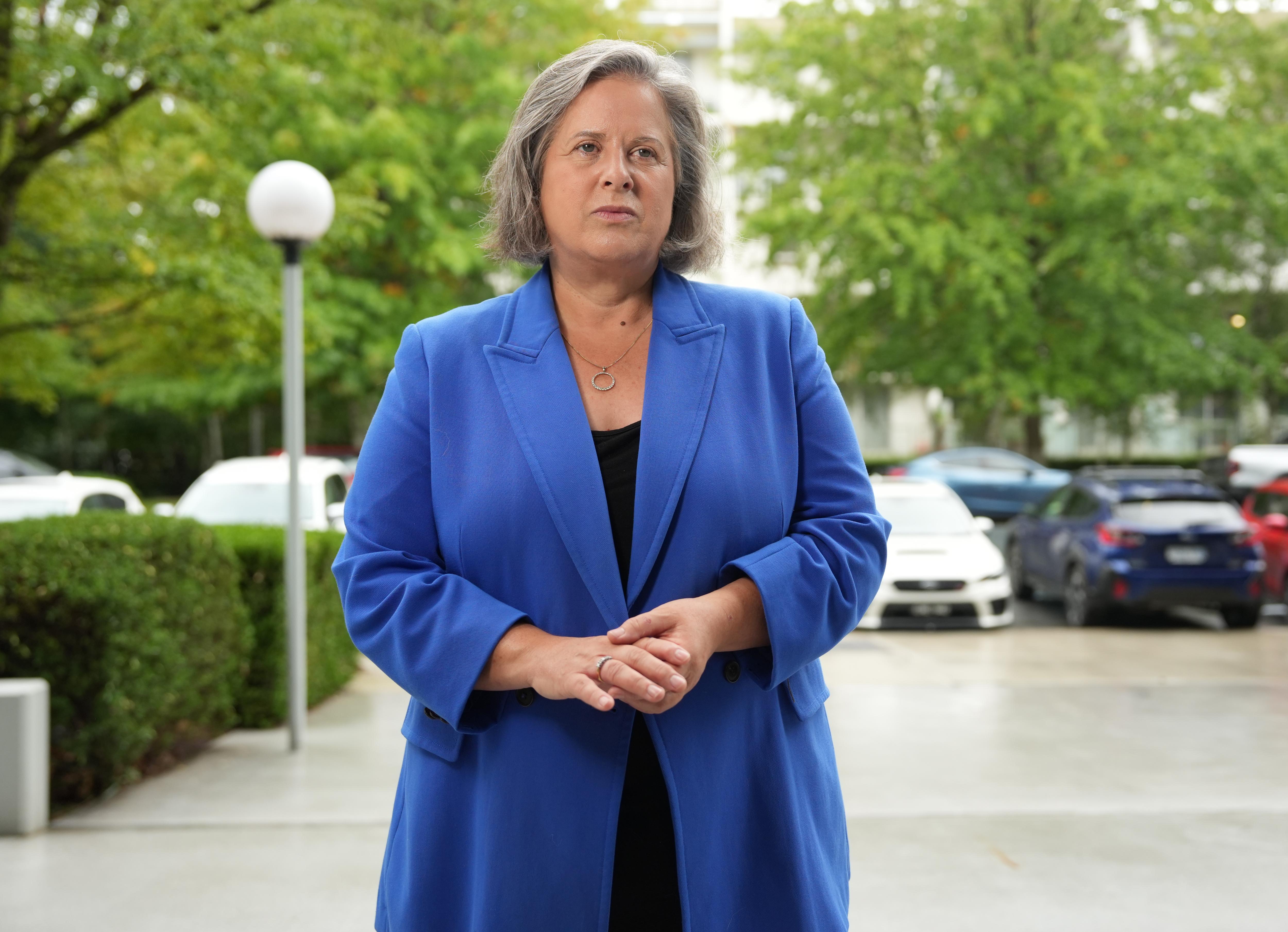 Una mujer vestida de azul se encuentra en una calle. 