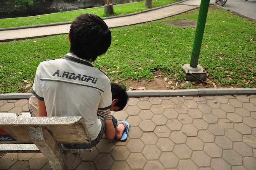 Two boys slumped on a park bench