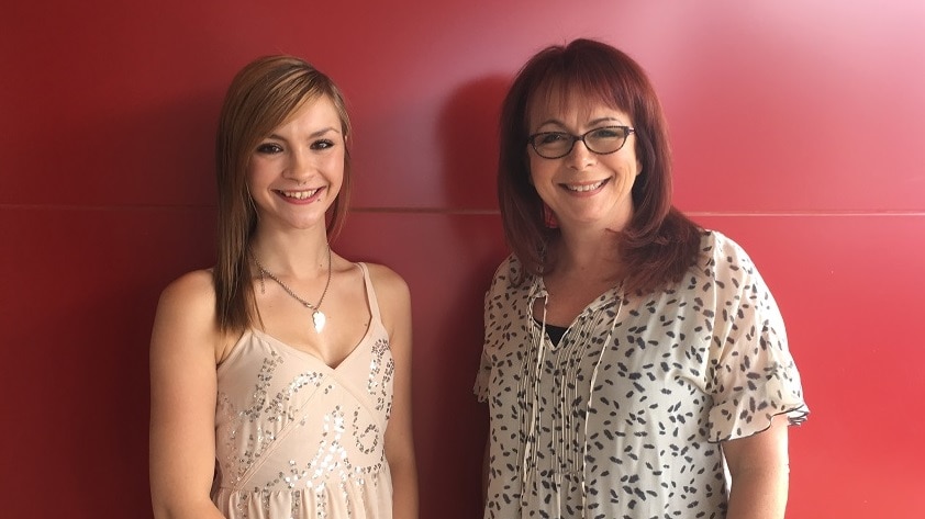 Young woman stands next to older woman, both smiling