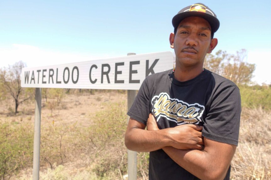 A man stands in front of the Waterloo Creek sign.