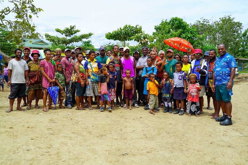 A group of people in brightly coloured clothing stand together for a photo