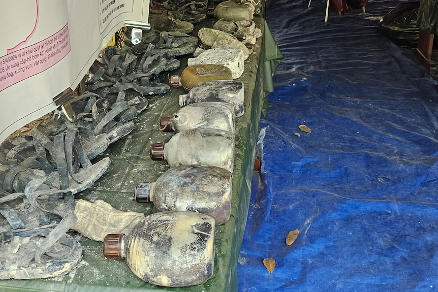 Water bottles and other artefacts spread along a table. 