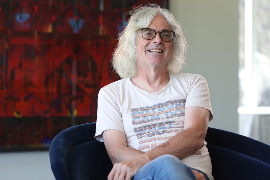 David Walsh, seated and wearing sunglasses and tshirt at MONA, 12 December 2018.