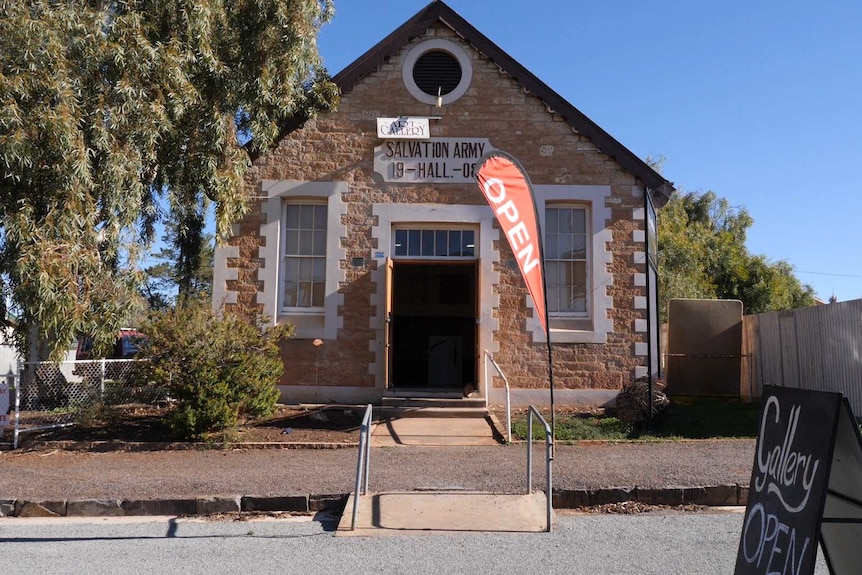 An old cream coloured stone building with a red open flag.