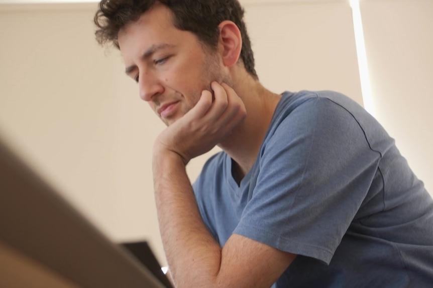 Man in blue t-shirt leaning on a table