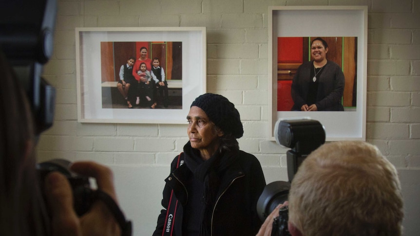 Photographers taking photos of Barbara McGrady, as she stands in front of her work.