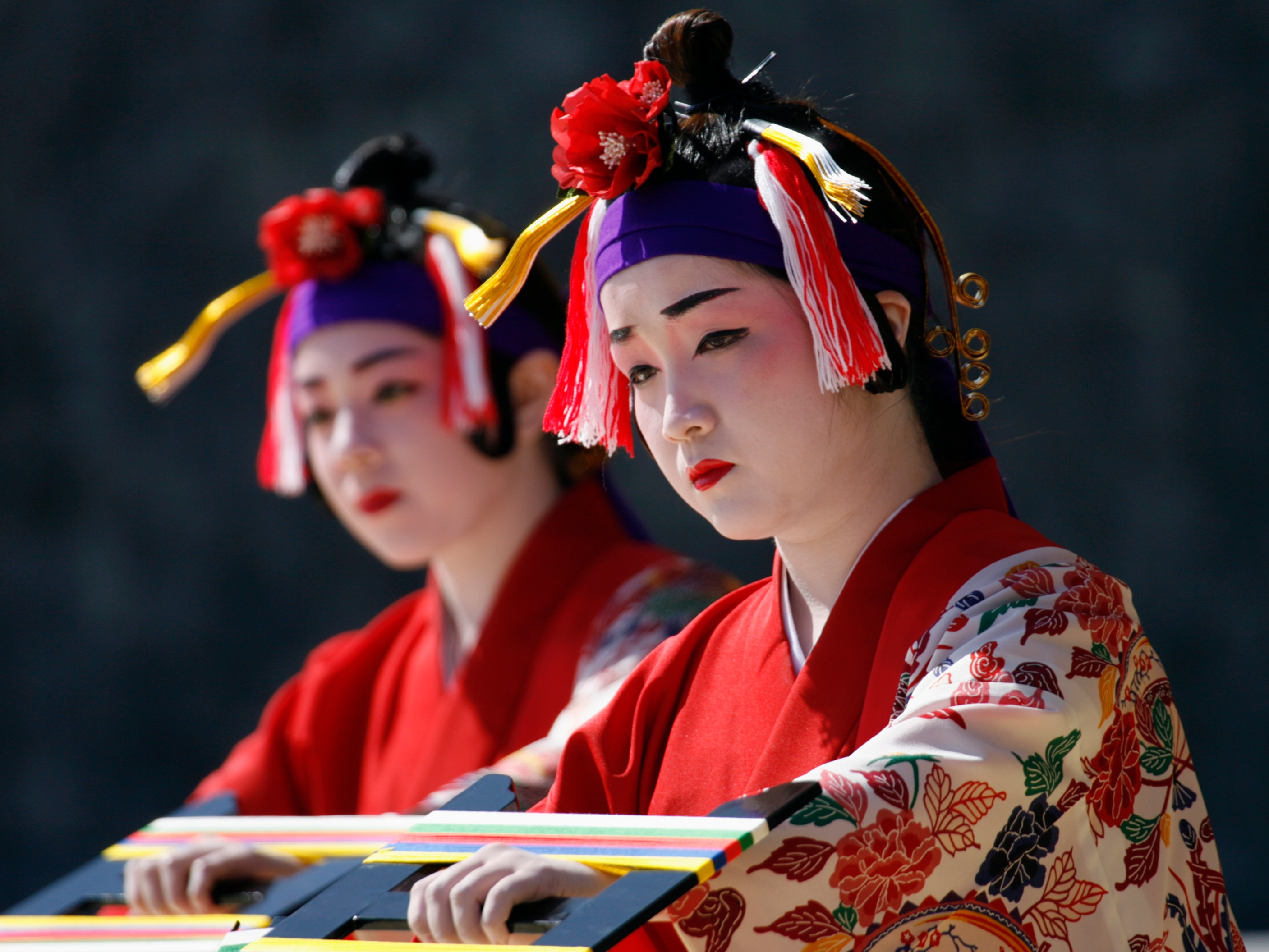 Dancers in pale makeup wearing colourful dress.