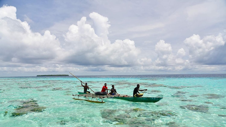 Men paddle on a raft on the crystal clear water.
