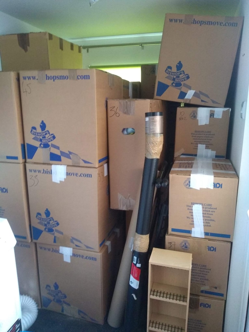Cardboard packing boxes of various sizes are piled up to the ceiling and sealed with masking tape.