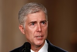 Close up of Neil Gorsuch in a suit speaking into a microphone