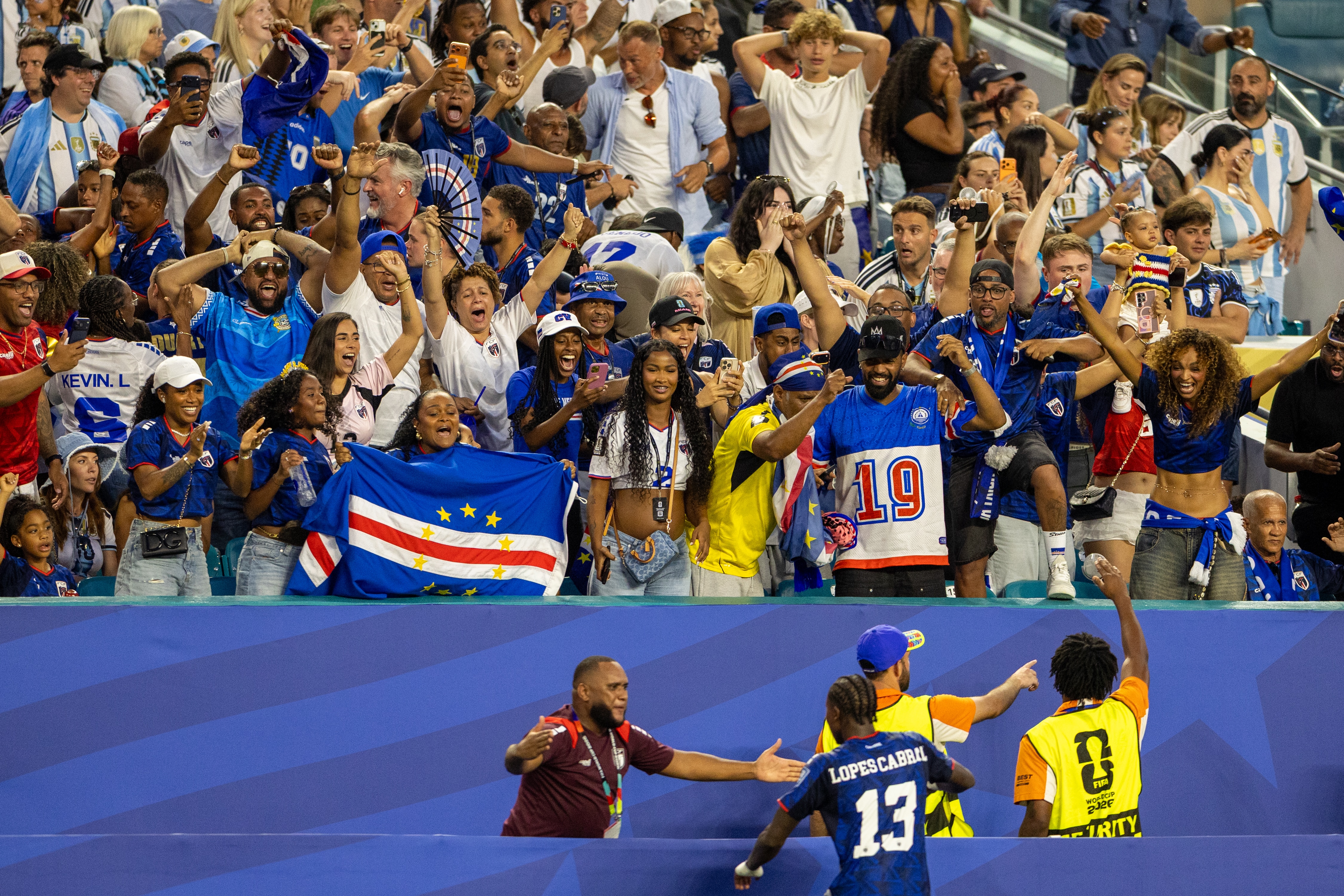 A Cabo Verde footballer stands looking up at his partner, family and fans after scoring a goal at the World Cup.