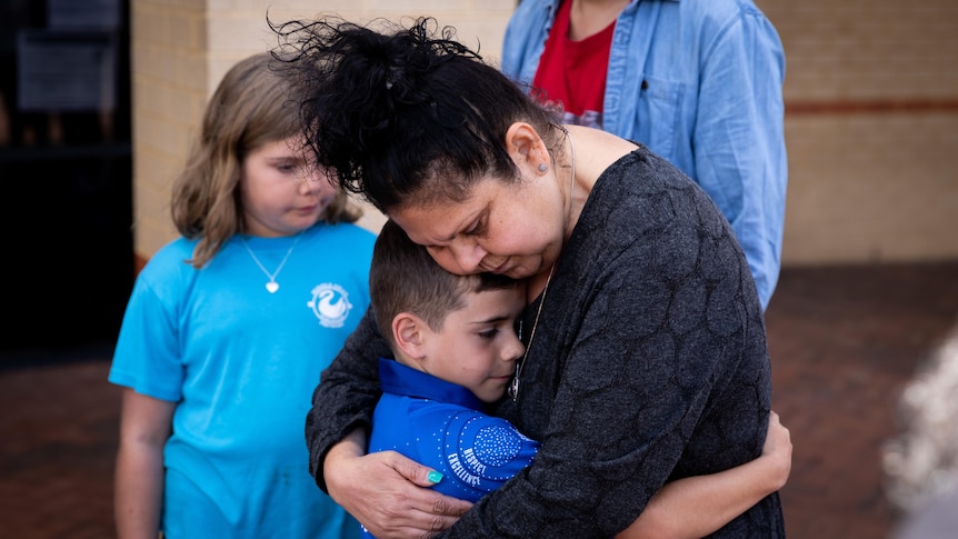 An Indigenous woman embraces a child