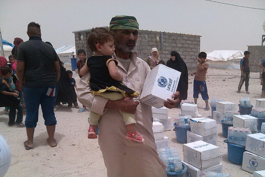 A displaced Iraqi resident and child collect emergency supplies after fleeing the fighting in Fallujah