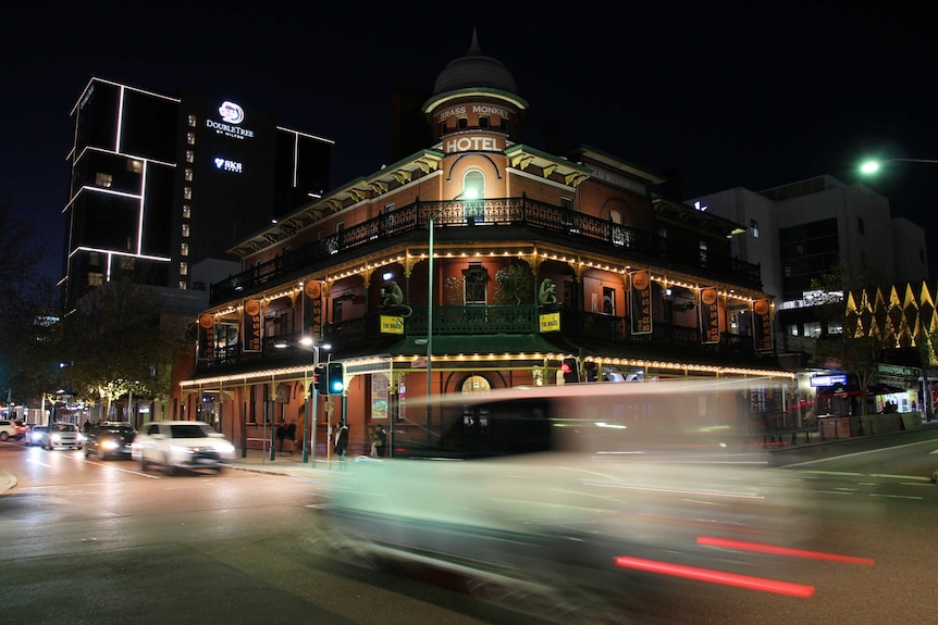 Cars pass through an intersection at night in an inner-city entertainment district