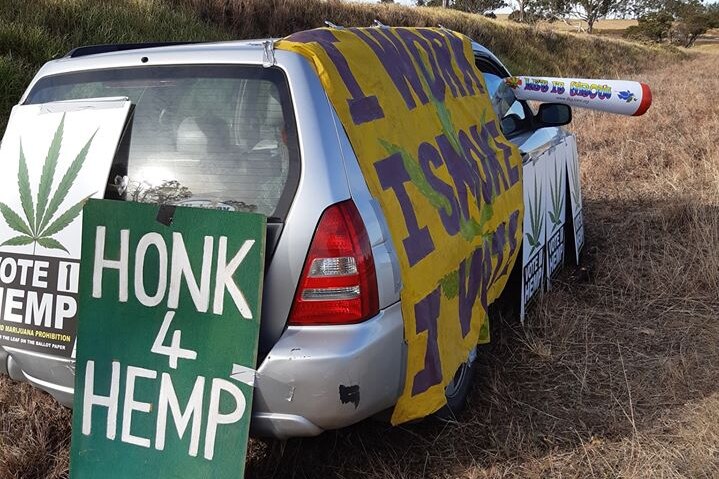 A 'honk 4 hemp' sign on a car with an inflatable cannabis joint sticking out the window.