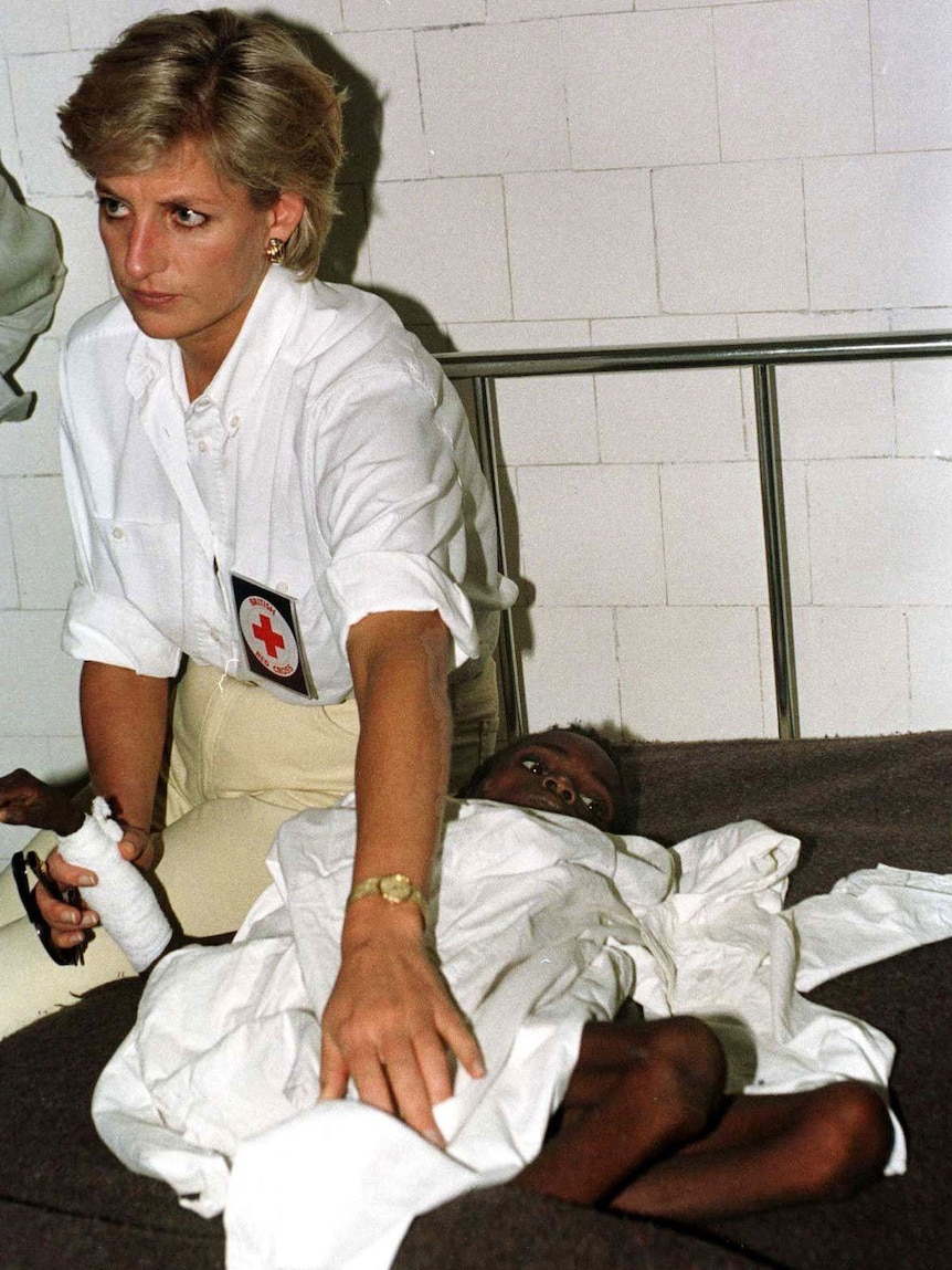 Princess Diana sits on a bed next to a sick African child.