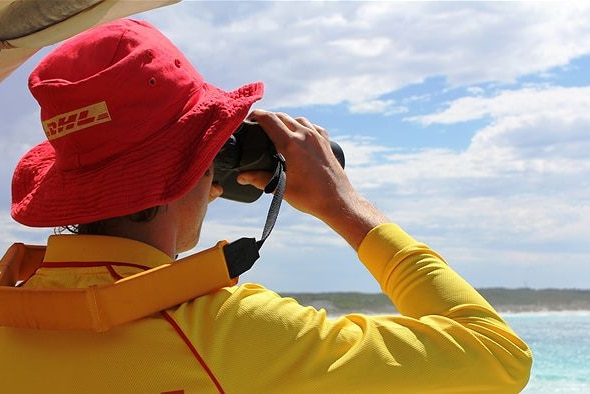Image of a lifesaver using binoculars looking out over the water