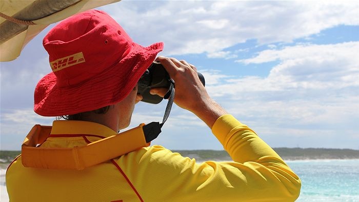 Image of a lifesaver using binoculars looking out over the water
