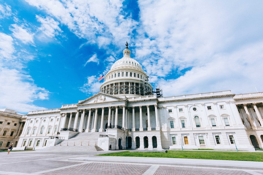 A wide shot of the capitol building, notably there is scaffolding around its iconic dome.