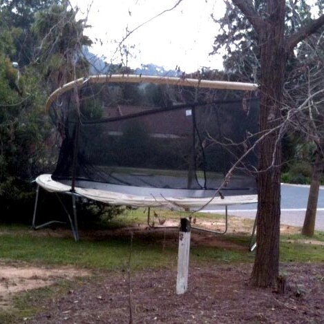 A trampoline sits in the front yard of a house after being blown there during high winds.