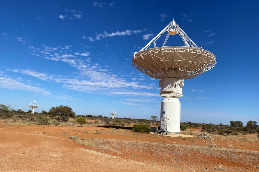 Wide shot of white radio telescope in the outback.