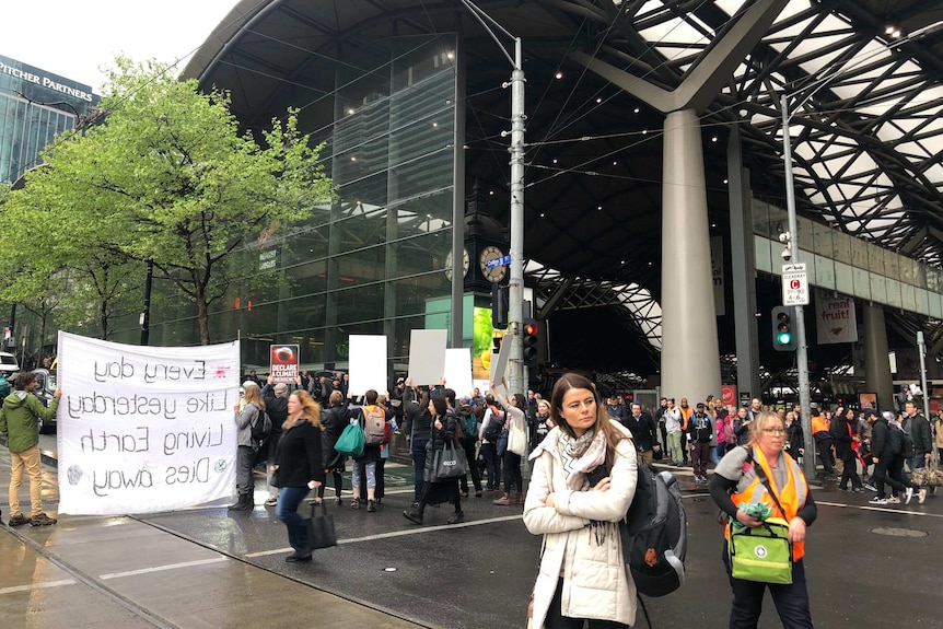 Climate activists demonstrate near Melbourne's Southern Cross Station, which has a high ceiling and is full of commuters.