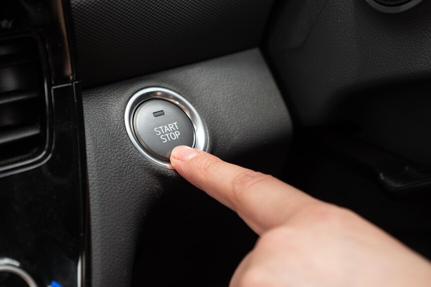 finger on start stop button on EV